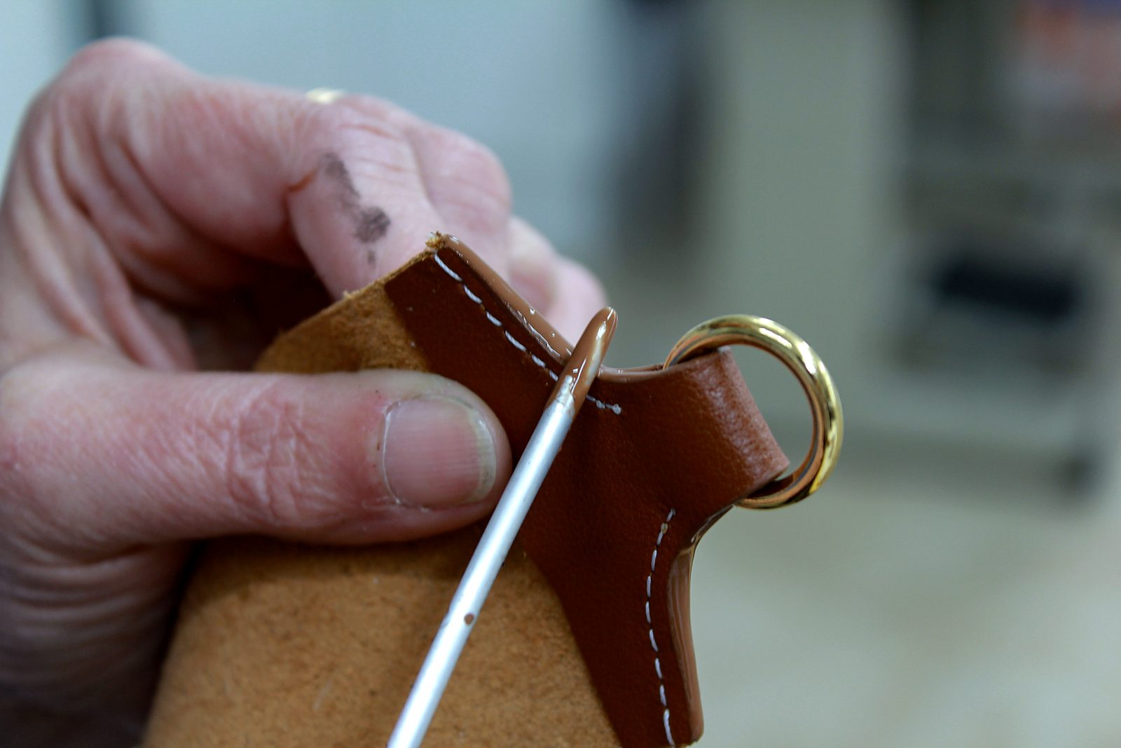 Hand painting the edge of a leather tab with a gold ring