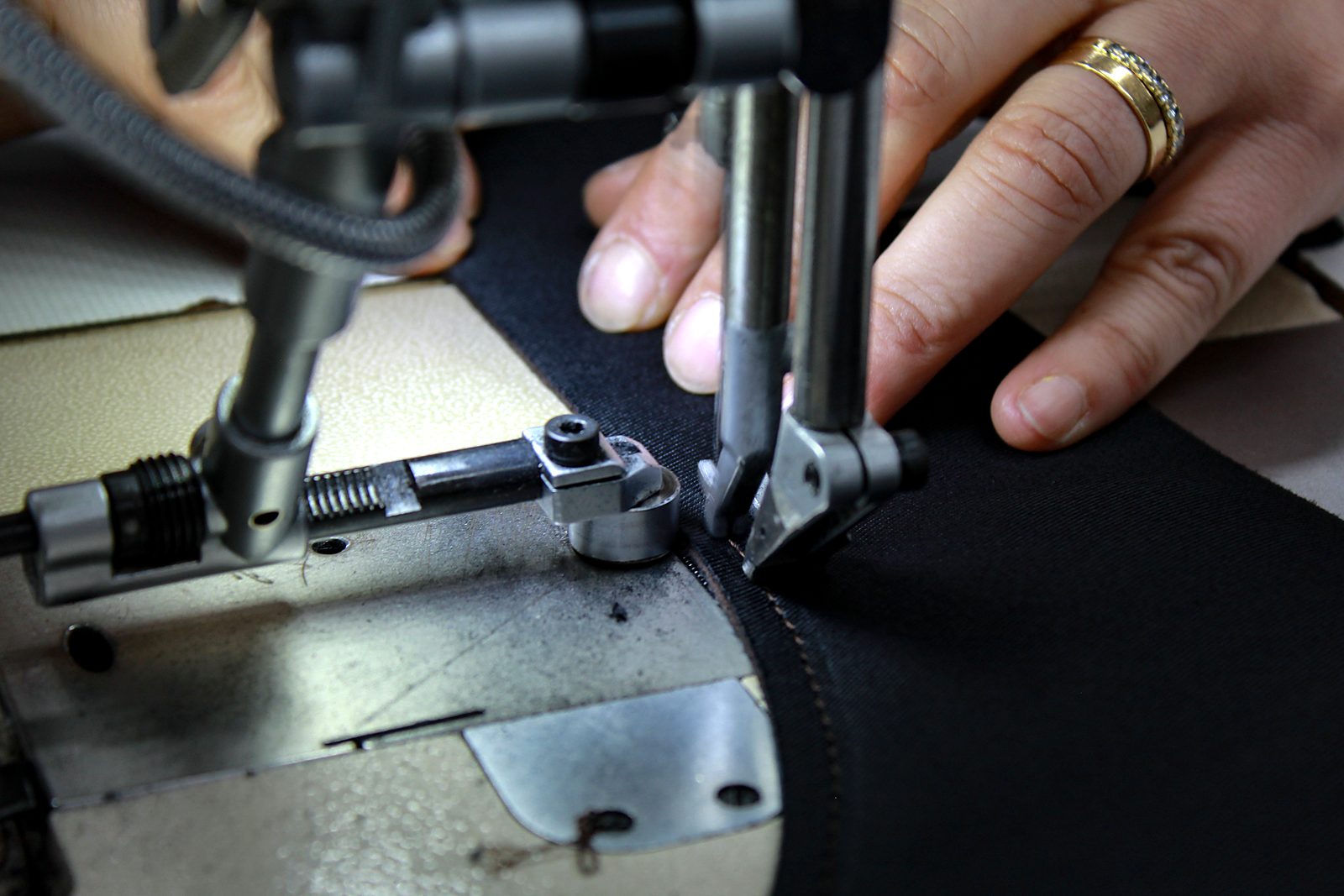 Artisan stitching black leather on an industrial sewing machine